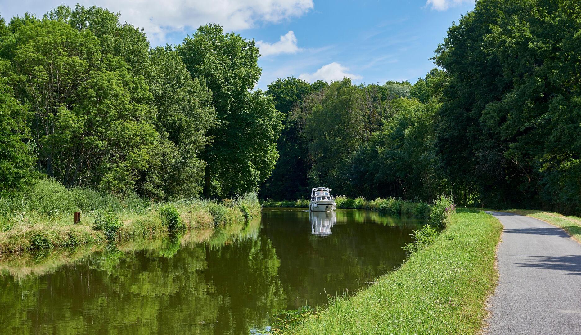 Boat on the Canal du Rhone au Rhin with towpath and cycling route.