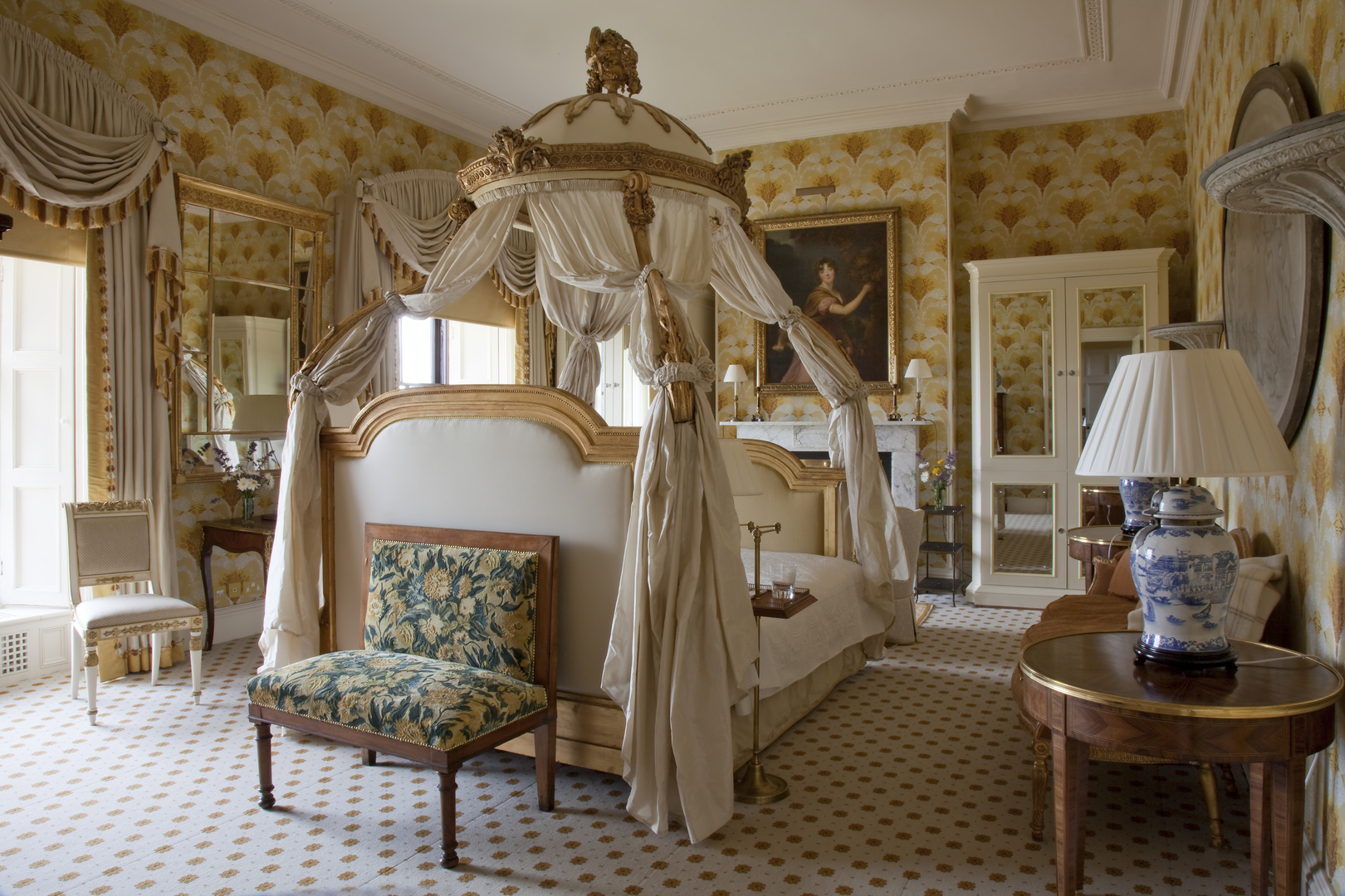 Ornate four-poster bed in a room with yellow patterned wallpaper.