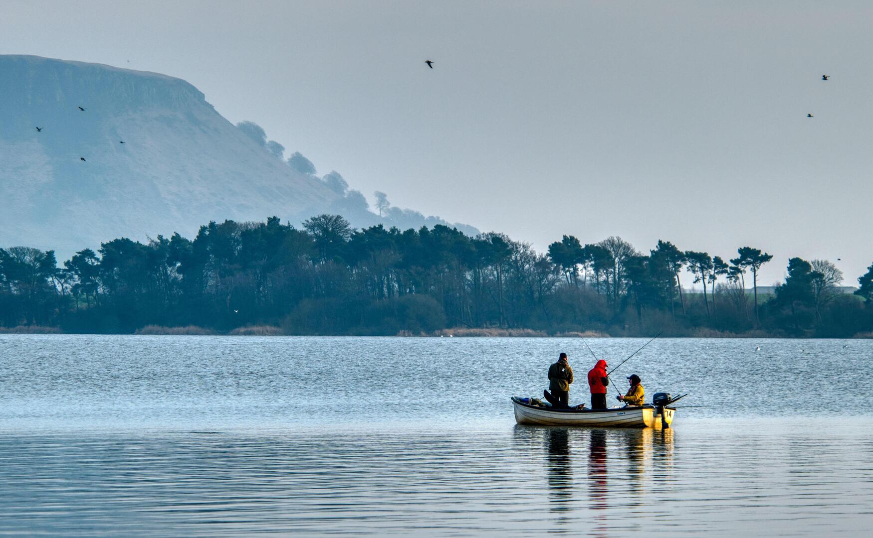 Three people fishing from a small boat on Loch Leven.