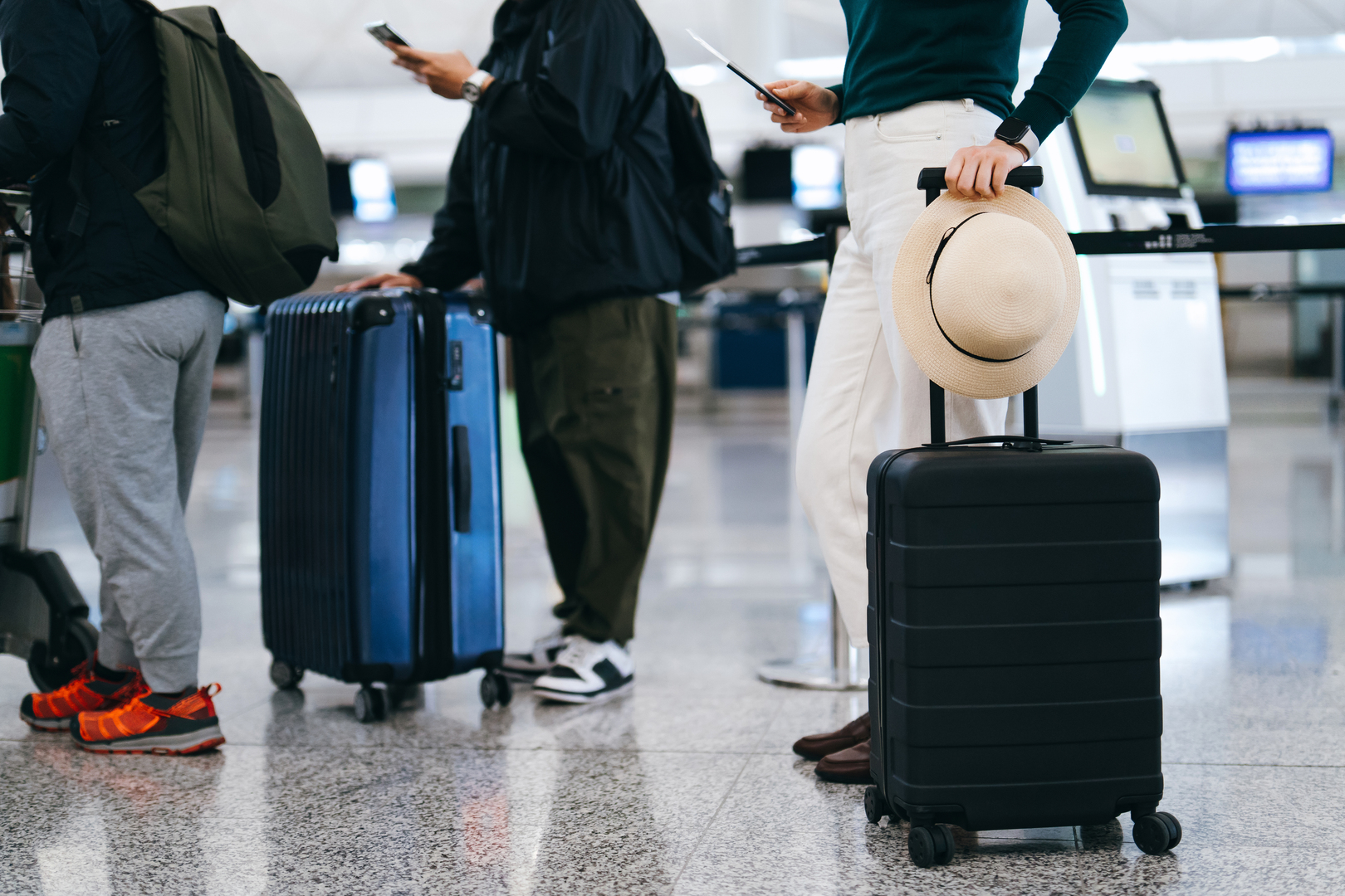 Passengers waiting in line at an airport check-in counter with their luggage.
